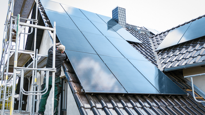 Person installing solar panels at the construction site of a house